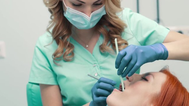 female dentist examines oral cavity of patient, close up