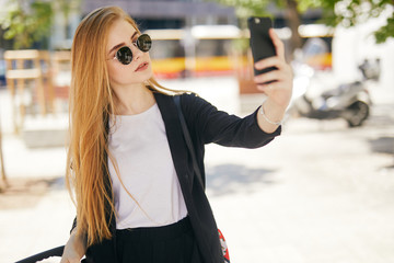 Pretty blonde girl taking selfie on the street