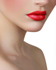 The beautiful fashionable young woman with creative cosmetics on a face. Red full lips on a blue background. Bright red cosmetics on a face, hands. Long neck and brilliant skin. Cosmetology