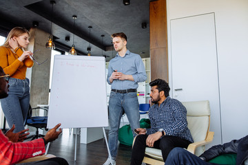 Multiethnic group of young businesspeople preparing for a presentation of their business idea using...
