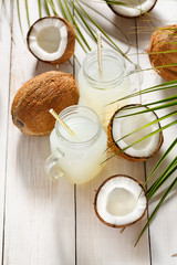 Coconut juice in jars on a white wooden board. Food background, selective focus