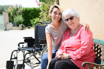 Fototapeta na wymiar cheerful old woman in a wheelchair with her young granddaughter outdoor in hospital