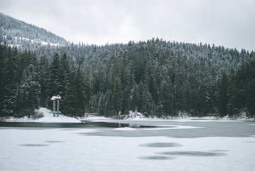 Beautiful mountain lake Synevyr in Ukraine. Frozen lake covered with snow against dark winter...