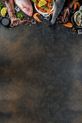 Fresh raw seafood squid shrimp oyster mussels fish with spices of herbs lemon on dark rusty background copy space top view