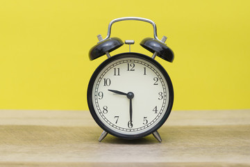 black bell clock on yellow background