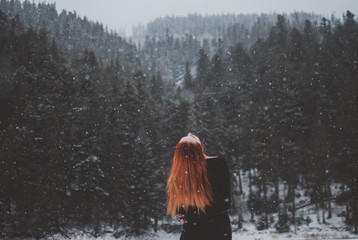 Handsome dark-eyed redhead girl standing by mountain Synevyr lake and looking up in the distance....
