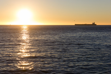 Cargo ship on the horizon at sunset heading to Valparaiso pier, Chile. International transportation, shipping concept