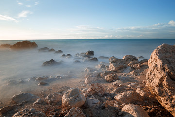 Fototapeta na wymiar Water rocks and ocean at dusk. Long exposure of a rocky coastline 