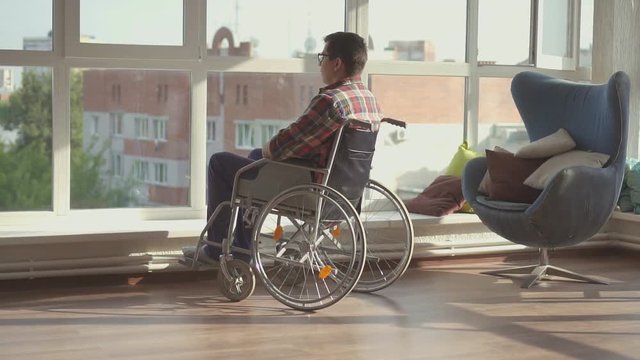 Disabled man sitting by the window in a wheelchair