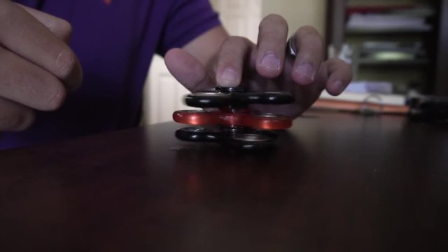 Man holds and spins three fidget spinners on top of each other.