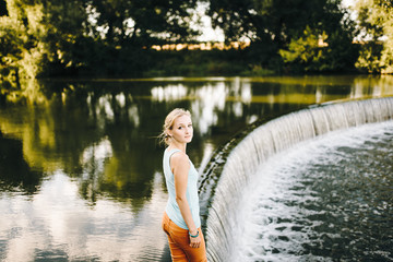 A dreamy, young, beautiful girl with long hair by the river. Beautiful woman by the lake. Single woman