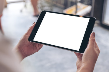 Mockup image of woman's hands holding black tablet pc with white blank desktop screen in cafe