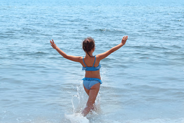child runs into the sea, a happy childhood