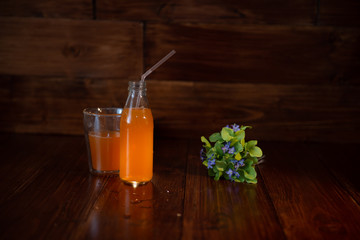 vintage bottle with juice, straw and flowers on wooden table