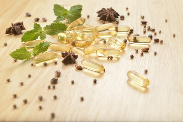 Medicine herb, Cod liver oil omega 3 gel capsules with healthy medicinal plant on wooden brown tone background