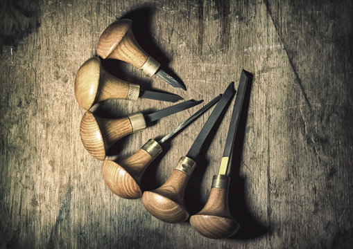 Jewelery tools: gravers at jeweler's workplace, brown background with a wooden structure, circle