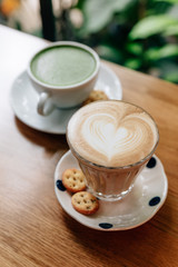 Latte art heart shape and green tea latte served on wooden table. Smooth and refresh when drinking.