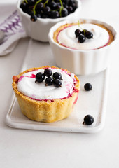 Pie with black currant and meringue on a white board.
