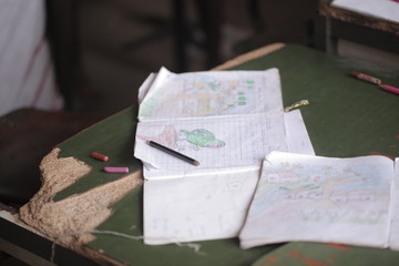 african education - close up of a school kid sitting inside a classroom, holding a pencil, indoors on a sunny day