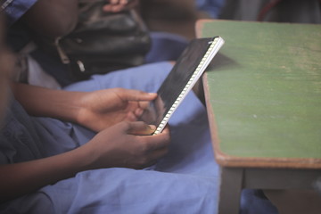 Obraz premium african education - close up of a school kid sitting inside a classroom, holding a pencil, indoors on a sunny day