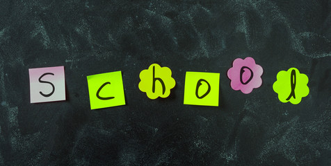 Sticky notes, with letters writing school, in various shapes and blank space, isolated on blackboard background.