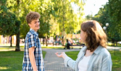 A female student meets a young man in park. In the summer in the city in nature. She stretches out her hand for communication. The guy smiles happily says Yes. Acquaintance in the city.