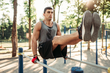 Man doing exercise on press using parallel bars