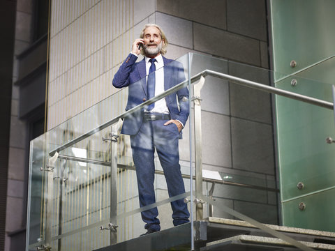 caucasian senior executive talking on cellphone on top of stairs