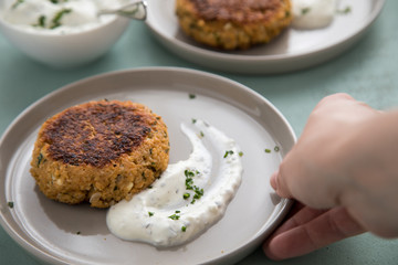 Woman eating vegetarian oatmeal cottage cheese patty with herbal quark dip