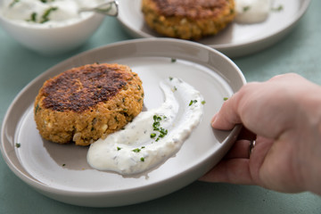 Woman eating vegetarian oatmeal cottage cheese patty with herbal quark dip