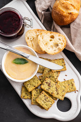 Chicken liver pate with bread on a white board over grey background.