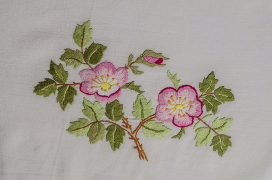 Sprig with pink flowers tea roses with a bud and leaves, embroidered a satin stitch on rough cotton fabric