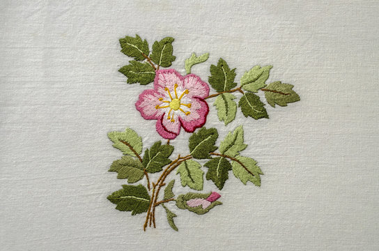 Flower pink tea rose with a bud and leaves, embroidered  a satin stitch on rough cotton fabric
