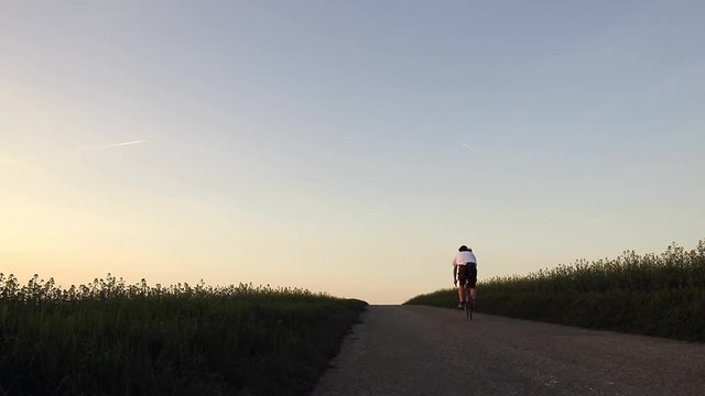Cyclist rides on a road after sunset