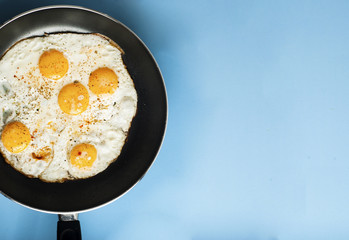 Breakfast Food Fried one egg in a frying pan isoalted on blue background copy space for text