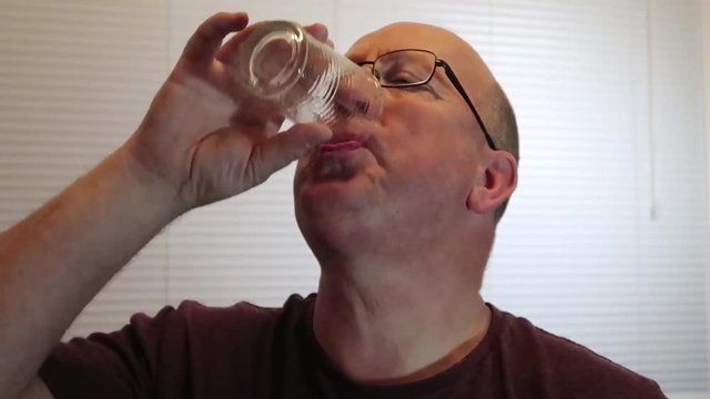 Man cringing after drinking medicine asprin from a glass