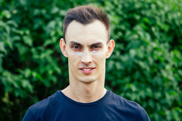 Portrait of a young smiling man in a park close-up on a green background