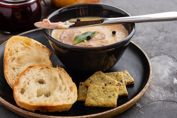 Homemade chicken liver pate or paste served with homemade bread and cranberry sauce over a rustic wooden board.