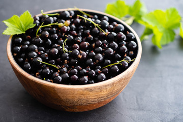 Blackcurrant berries with leaves, blackcurrant in a bowl.