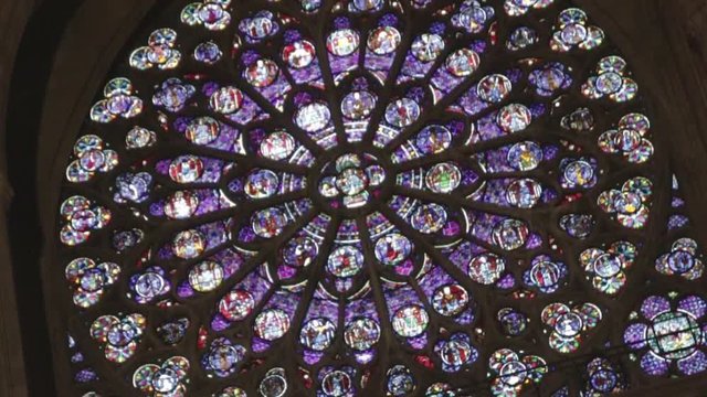 Handheld moving shot of huge sandglass window in old french church