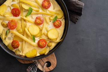 Spanish potato omelet called tortilla de patatas on a black background. Rustic style.