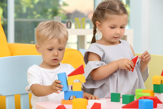 Cute children playing with constructor on table at home