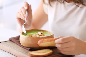 Obraz na płótnie Canvas Woman eating tasty spinach soup in kitchen
