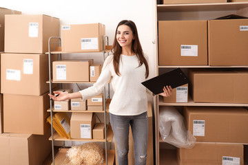 Young woman preparing parcels for shipment to client in home office