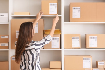 Young woman preparing parcels for shipment to client in home office