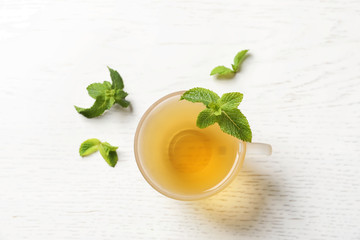 Cup with hot aromatic mint tea and fresh leaves on table, top view
