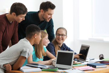 Group of teenagers doing homework with teacher in classroom