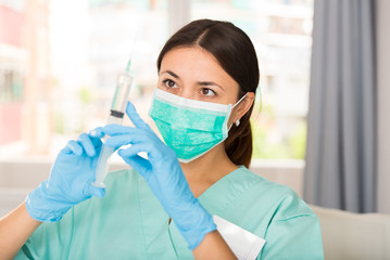 Girl nurse in mask holding syringe for injection in clinic