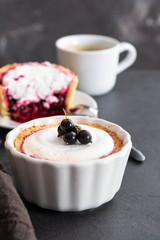 Pie with fruit and berry filling and meringue with a cup of coffee on a black background.