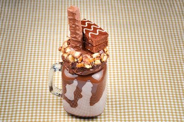 Chocolate extreme milkshake with brownie cake, chocolate paste and sweets. Crazy freakshake food trend. Copy space